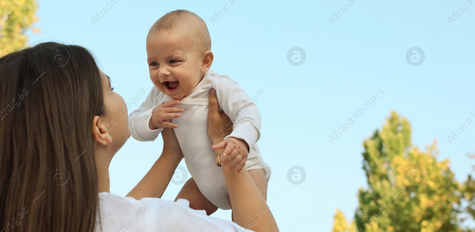 Image of Happy mother with cute baby in park on sunny day, space for text. Banner design 