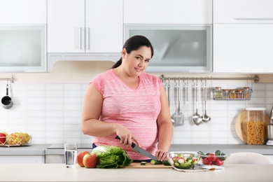 Photo of Woman preparing vegetable salad on table in kitchen. Healthy diet