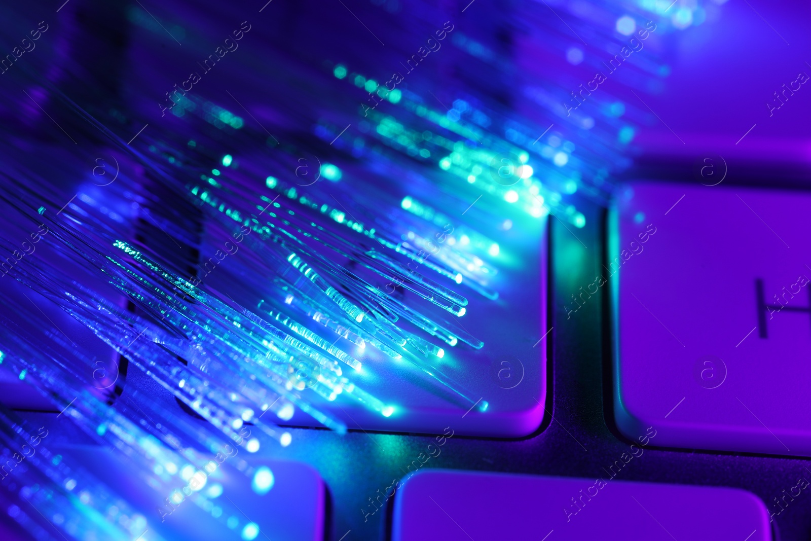 Photo of Optical fiber strands transmitting different color lights on computer keyboard, macro view