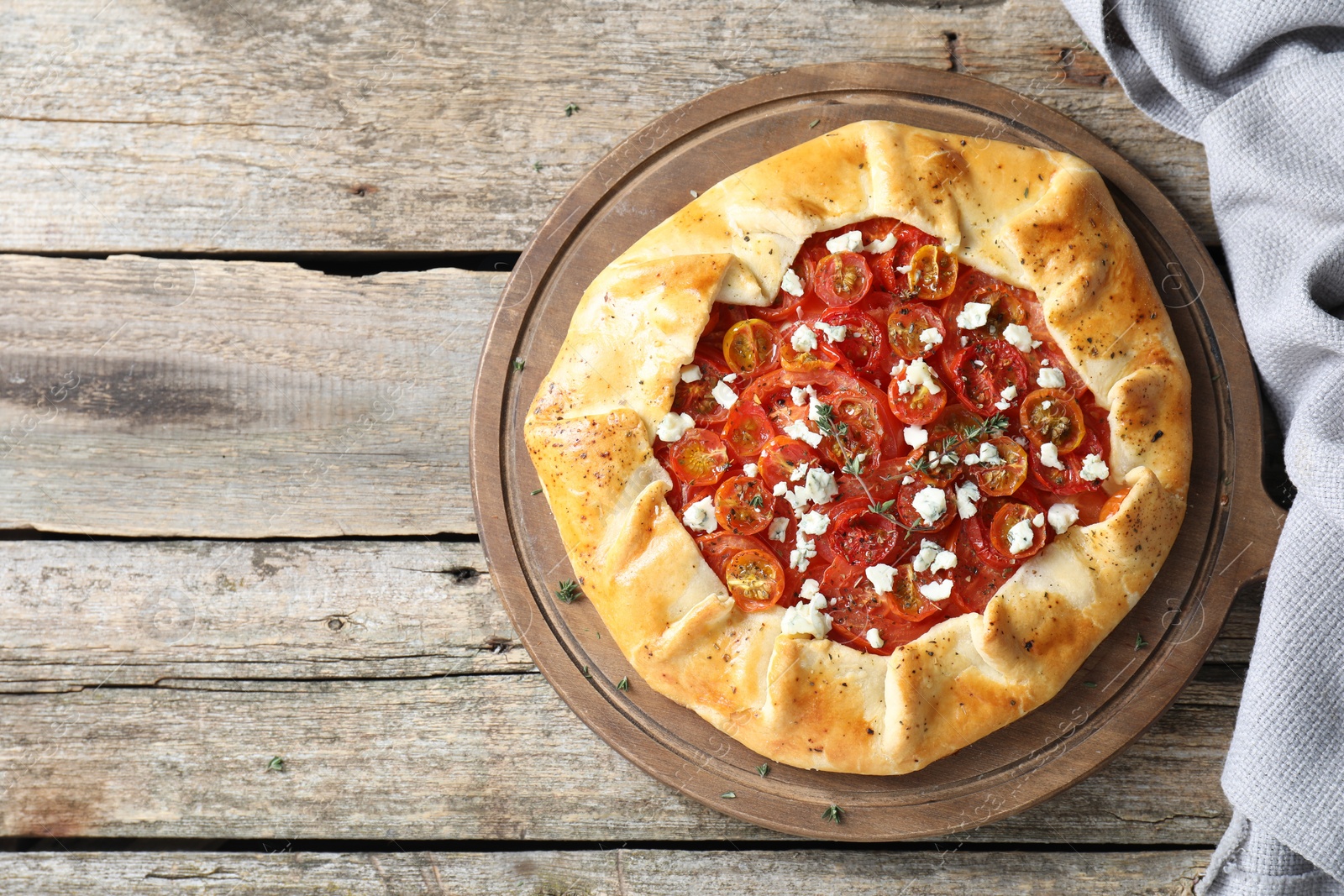 Photo of Tasty galette with tomato, thyme and cheese (Caprese galette) on wooden table, top view. Space for text