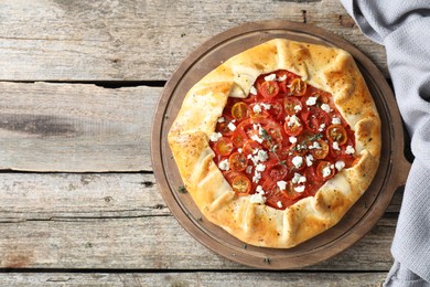 Photo of Tasty galette with tomato, thyme and cheese (Caprese galette) on wooden table, top view. Space for text