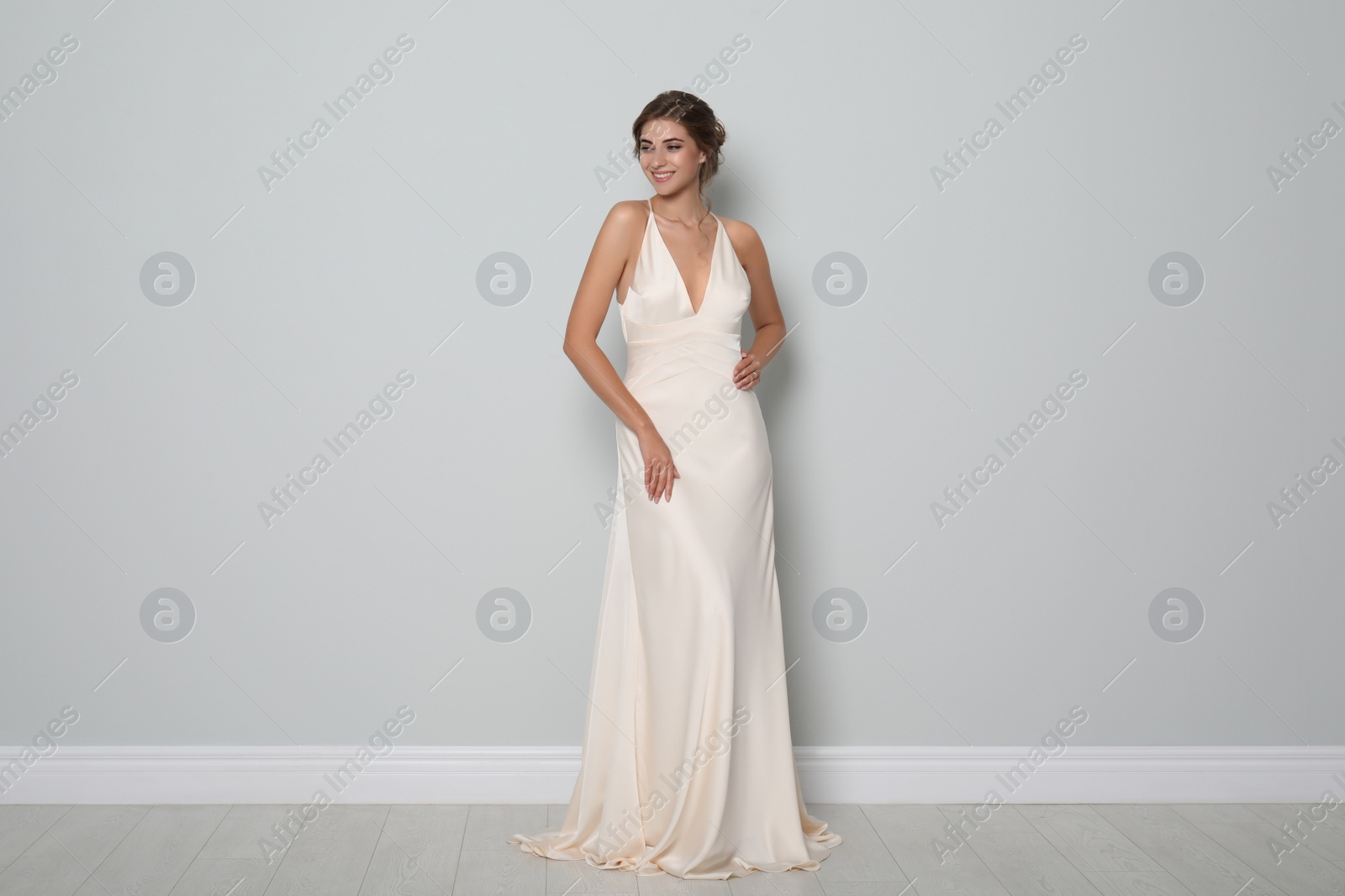 Photo of Young bride wearing beautiful wedding dress near light grey wall