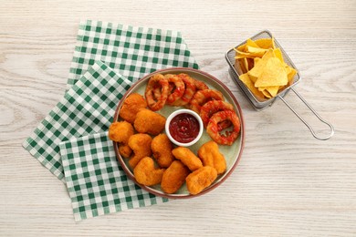 Different delicious fast food served with ketchup on white wooden table, flat lay