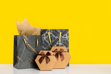 Photo of Shopping bags and gift boxes on yellow background. Space for text