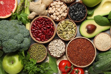 Different vegetables, seeds and fruits on grey table, flat lay. Healthy diet