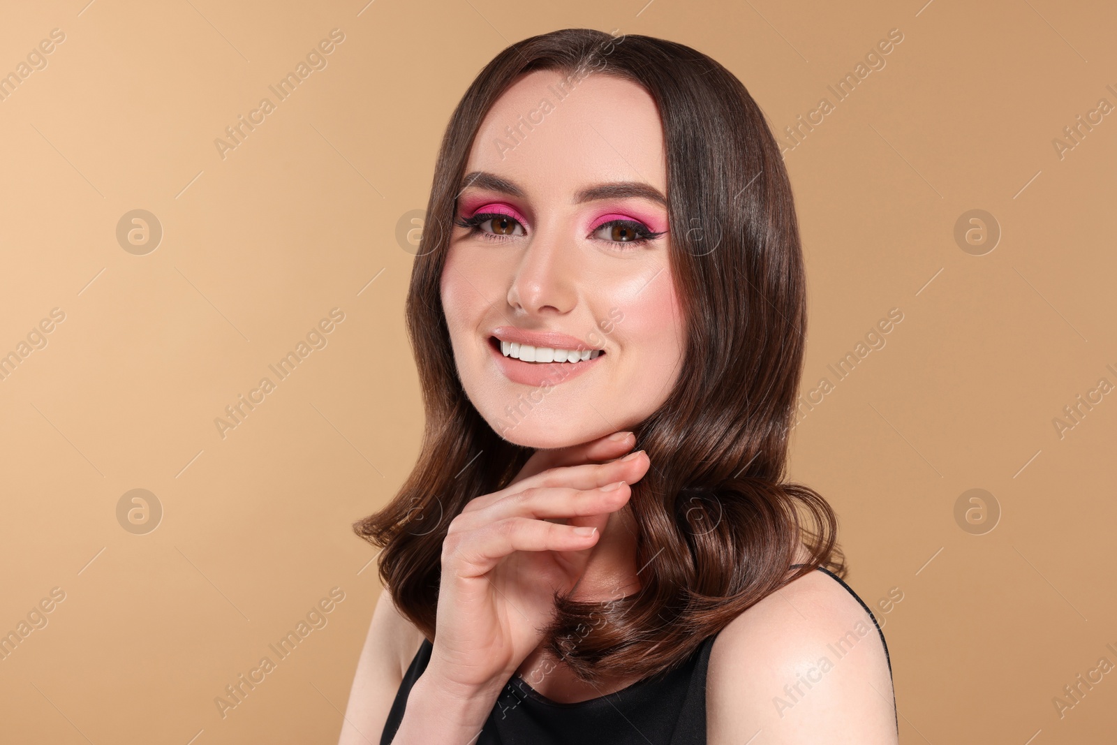 Photo of Portrait of beautiful young woman with makeup and gorgeous hair styling on beige background