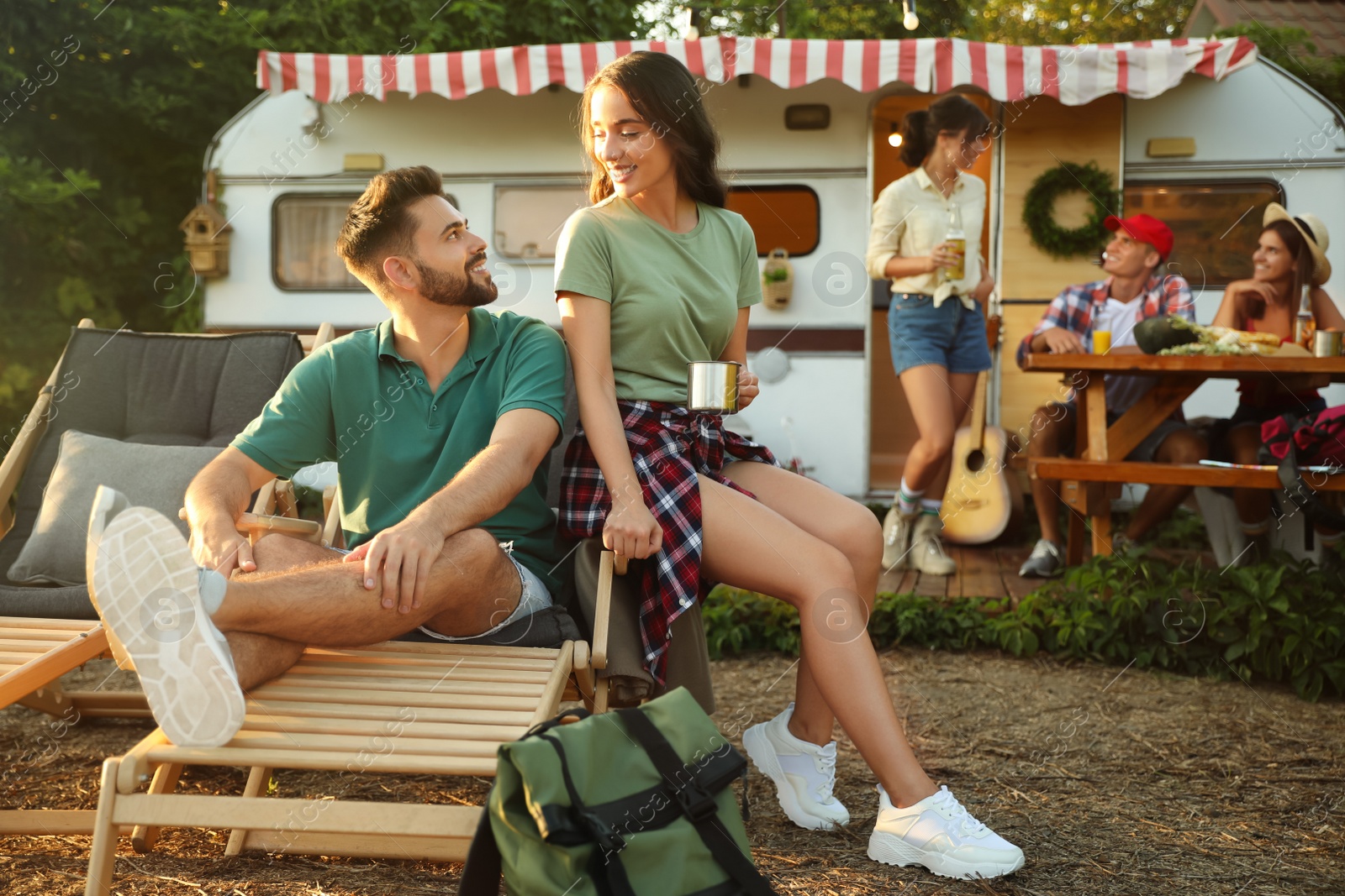 Photo of Happy friends resting near motorhome. Camping season