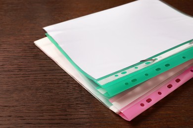 Photo of File folders with punched pockets on wooden table, closeup. Space for text