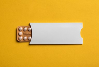 Photo of Birth control pills on yellow background, top view