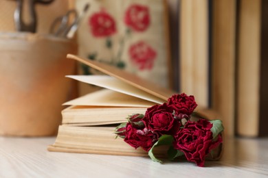 Photo of Beautiful dried flowers in book on wooden table