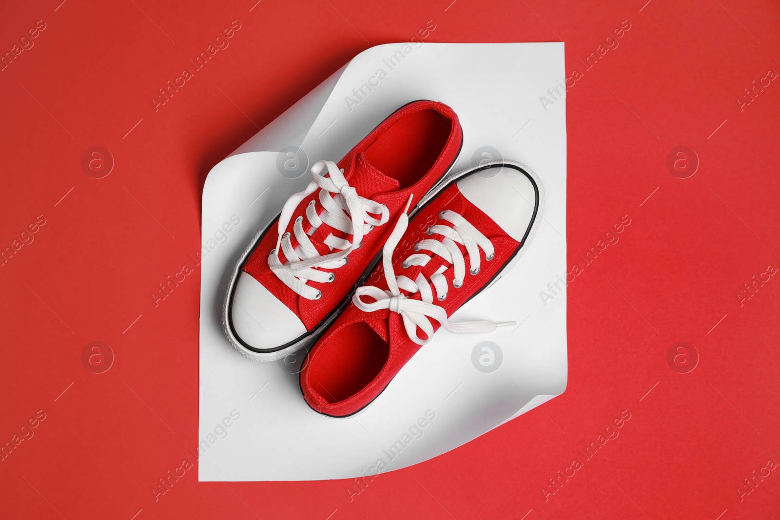 Photo of Pair of red classic old school sneakers on color background, flat lay