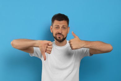 Photo of Man showing thumbs up and down on light blue background