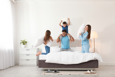 Photo of Happy family having pillow fight in bedroom