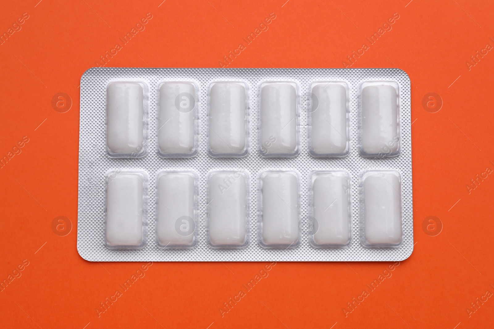 Photo of Blister with chewing gums on orange background, top view