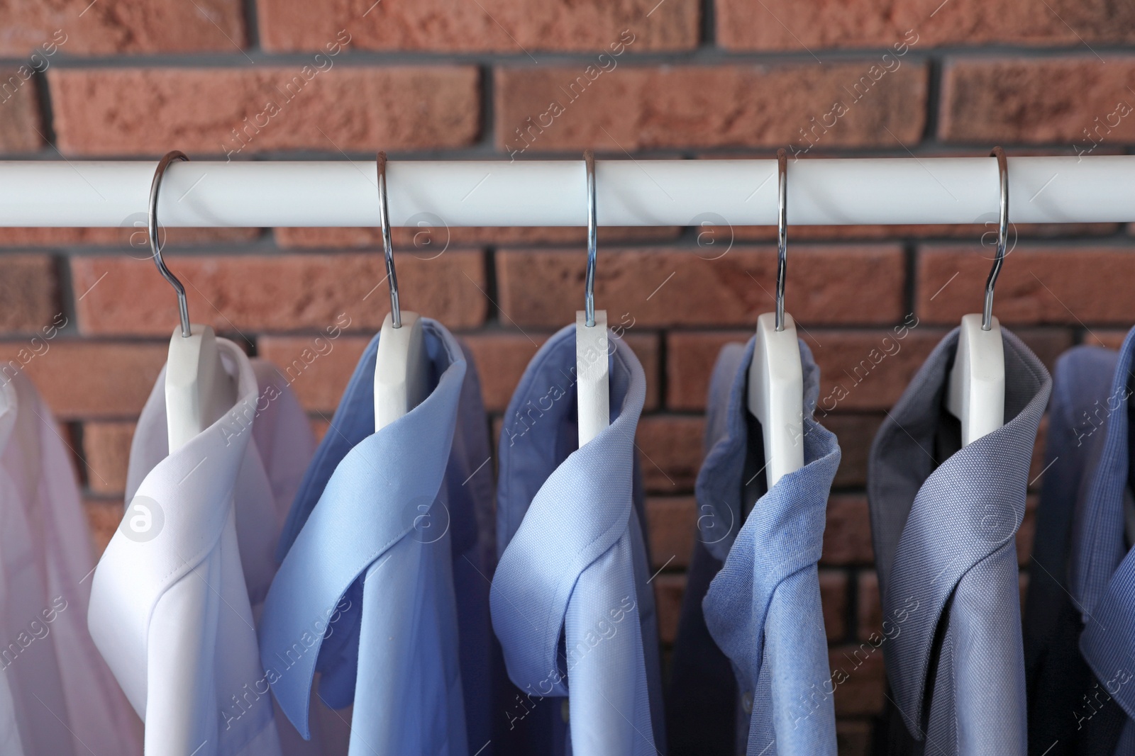 Photo of Wardrobe rack with men's clothes near brick wall