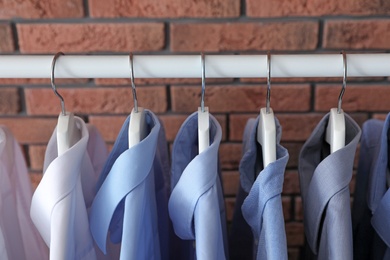 Photo of Wardrobe rack with men's clothes near brick wall