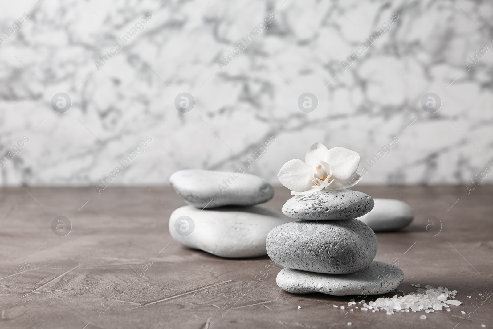 Photo of Spa stones and orchid flower on grey table. Space for text