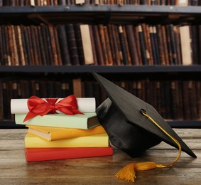 Image of Graduation hat, books and diploma on wooden table in library