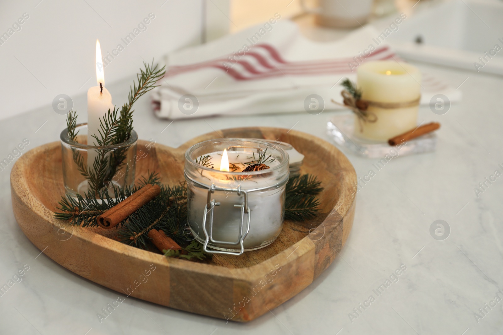 Photo of Burning scented conifer candle on white table indoors