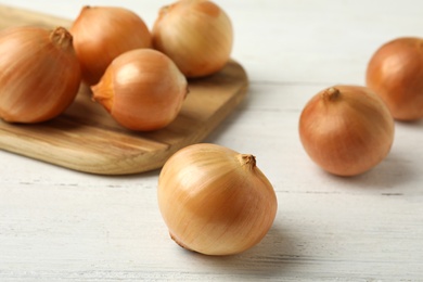 Ripe onions on white wooden table, closeup