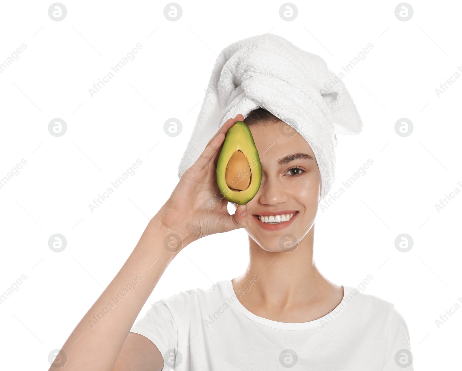 Photo of Happy young woman with towel holding avocado on white background. Organic face mask