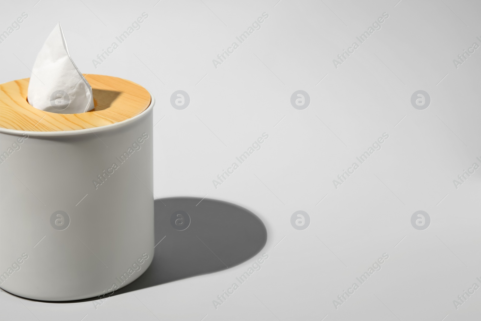 Photo of Holder with paper tissues on light grey background, closeup. Space for text