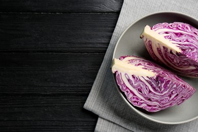Photo of Fresh red cabbage in bowl on black wooden table, top view. Space for text