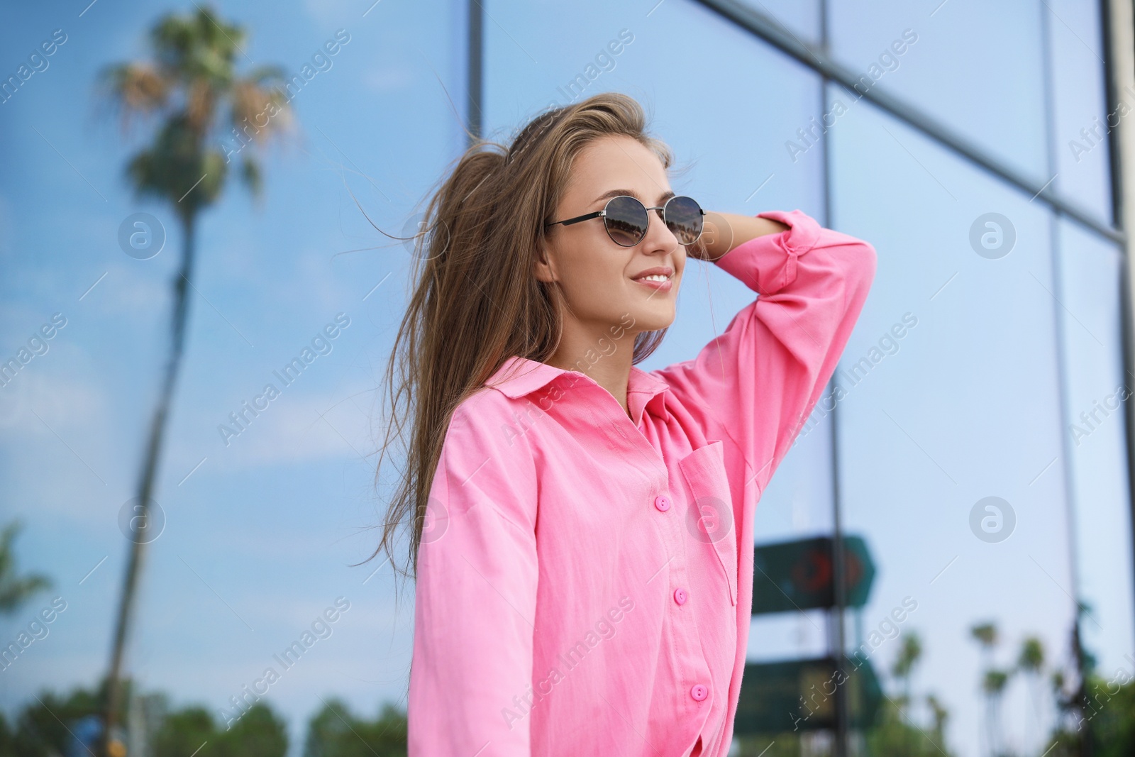 Photo of Portrait of beautiful young woman in stylish sunglasses near building outdoors