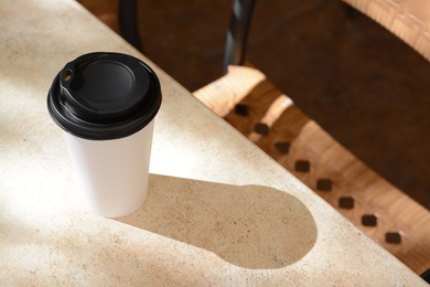 Photo of Takeaway coffee cup on beige table in cafe, space for text