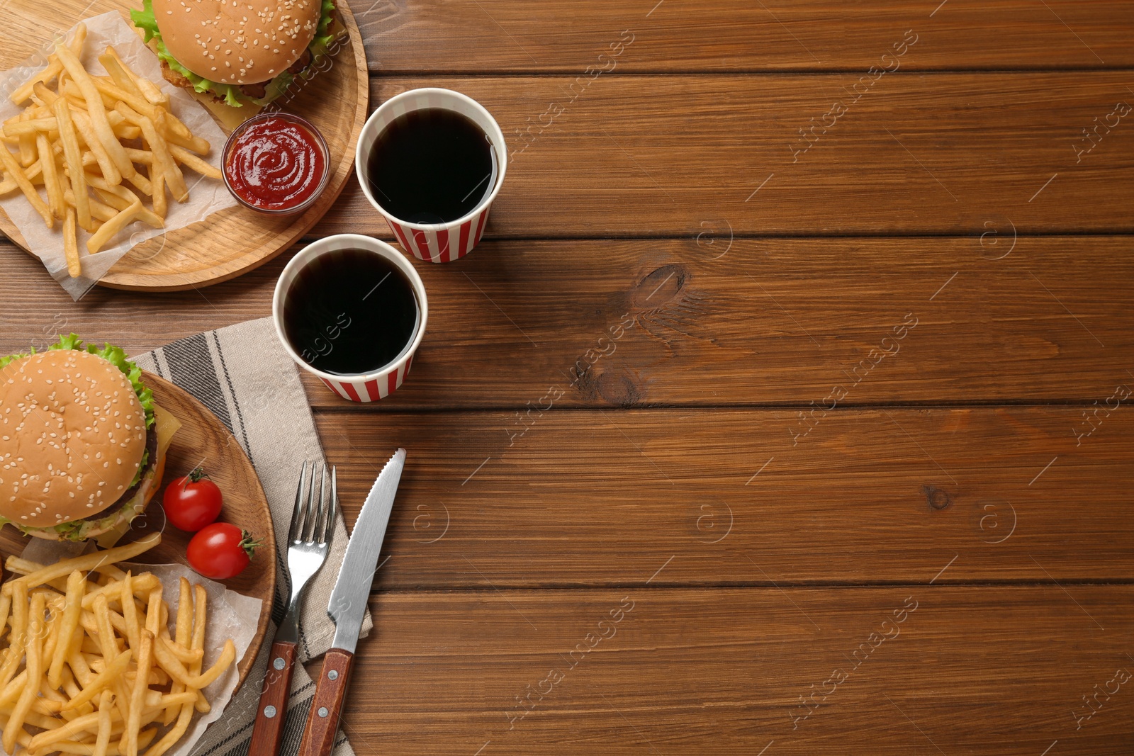 Photo of Flat lay composition with delicious fast food menu on wooden table. Space for text