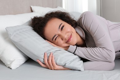 Happy beautiful African American woman lying in bed at home