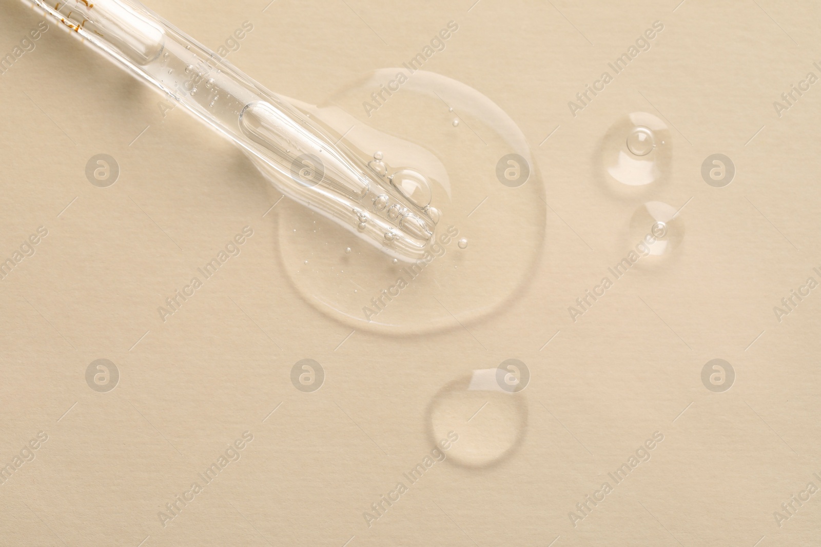 Photo of Glass pipette and transparent liquid on beige background, top view