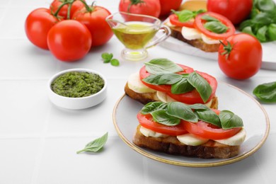 Photo of Delicious Caprese sandwiches with mozzarella, tomatoes, basil and pesto sauce on white table. Space for text