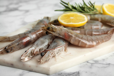 Photo of Fresh raw shrimps on marble table, closeup