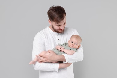 Photo of Father with his cute baby on grey background