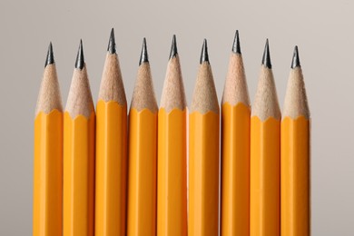 Many sharp graphite pencils on grey background, macro view