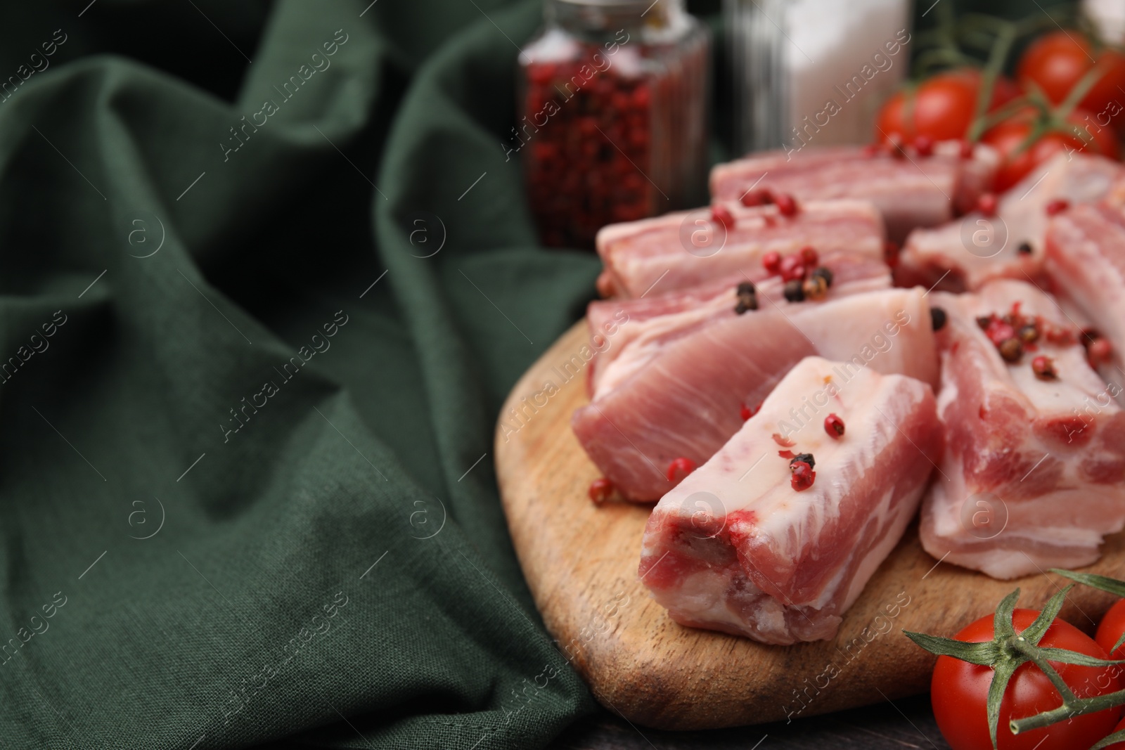 Photo of Cut raw pork ribs with peppercorns on table, closeup. Space for text