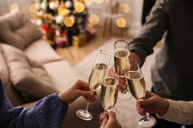 Photo of People clinking glasses with champagne at home, closeup