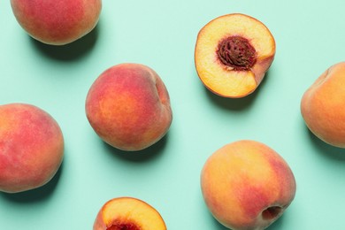 Photo of Cut and whole fresh ripe peaches on light blue background, flat lay