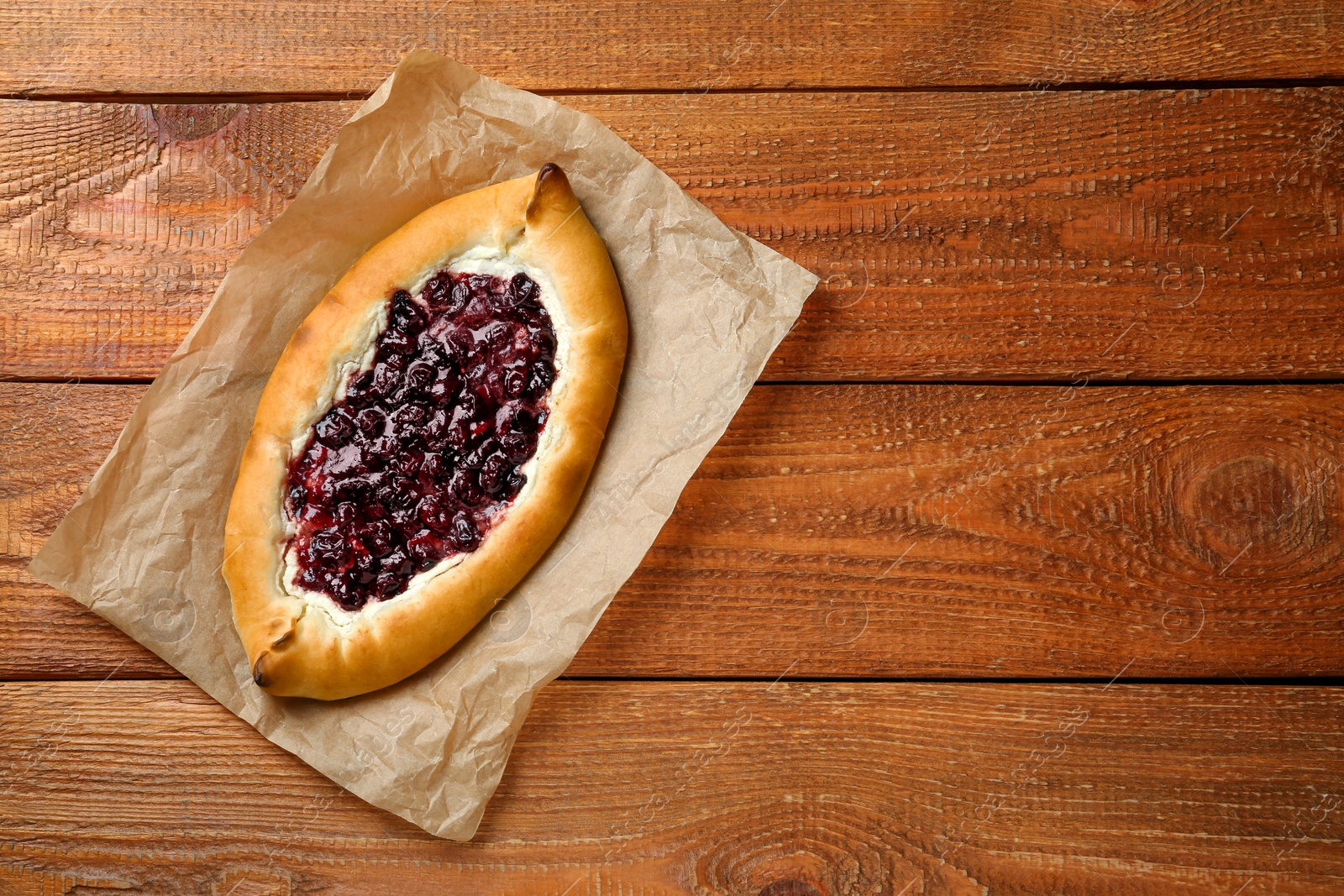 Photo of Delicious sweet cottage cheese pastry with cherry jam on wooden table, top view. Space for text