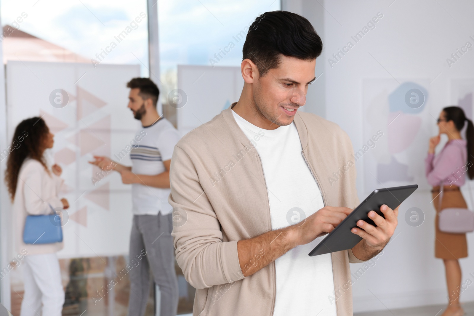 Photo of Happy man with tablet at exhibition in art gallery