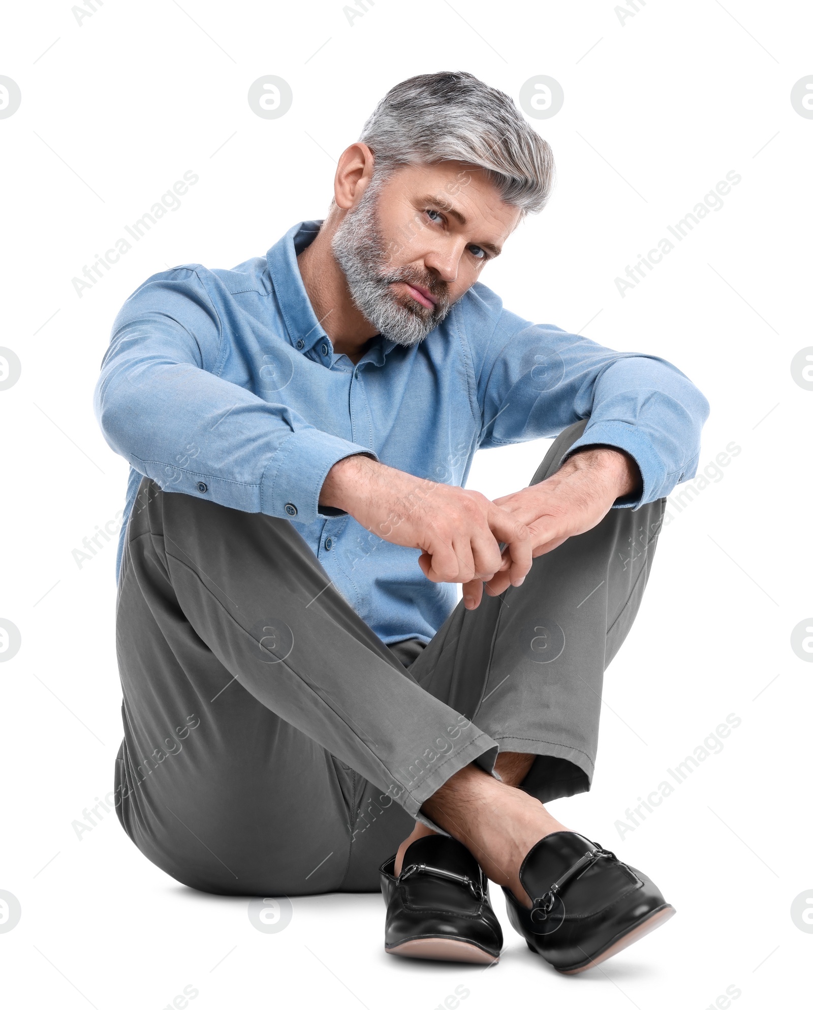 Photo of Mature businessman in stylish clothes sitting on white background