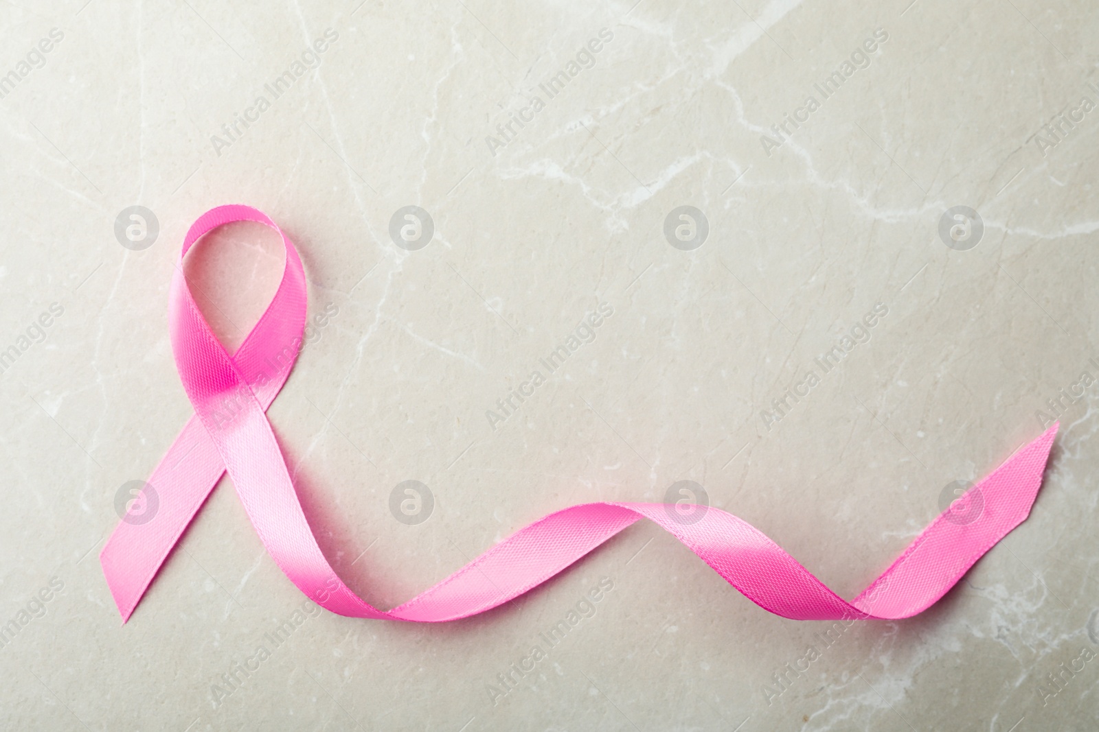 Photo of Pink ribbon on grey background, top view with space for text. Breast cancer awareness concept