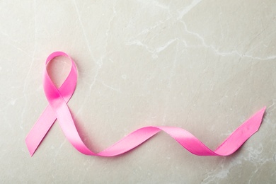 Pink ribbon on grey background, top view with space for text. Breast cancer awareness concept