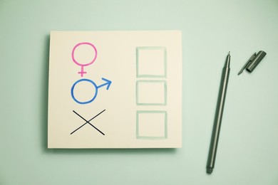Photo of Gender equality. Pen near card with cross mark, male and female symbols on light grey background, flat lay