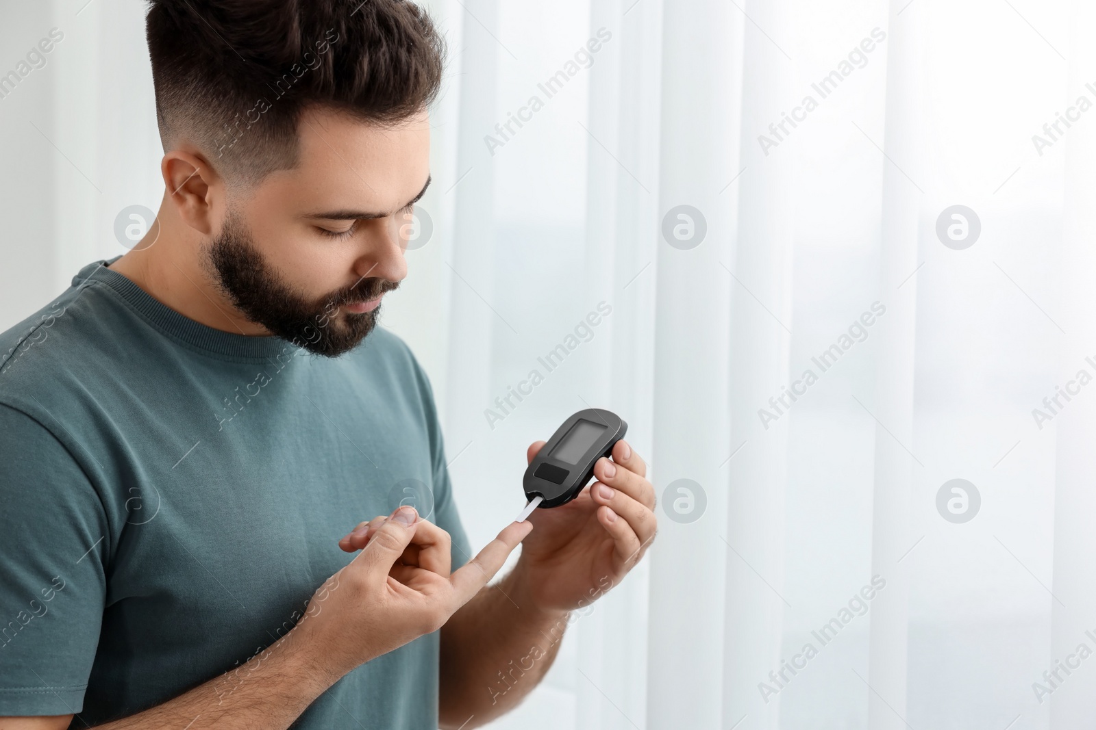 Photo of Diabetes test. Man checking blood sugar level with glucometer at home. Space for text