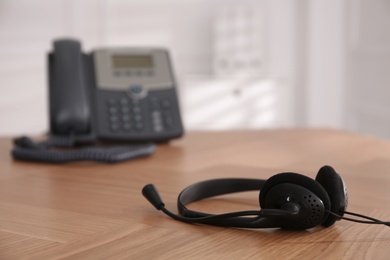 Photo of Headset on wooden table indoors, space for text. Hotline service