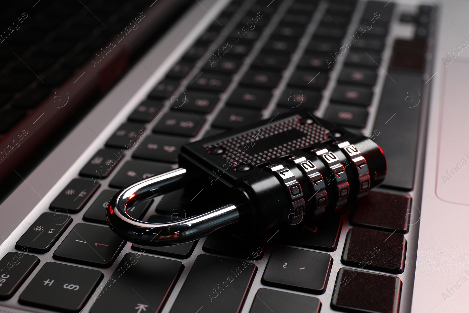 Photo of Cyber security. Metal combination padlock on laptop, closeup