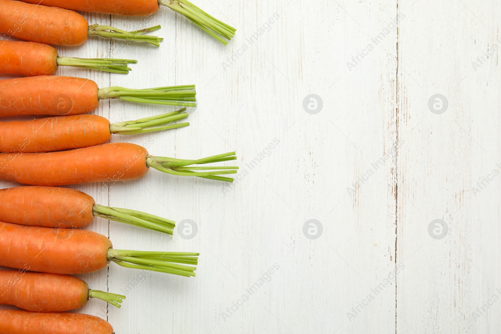 Photo of Ripe carrots on wooden background, top view