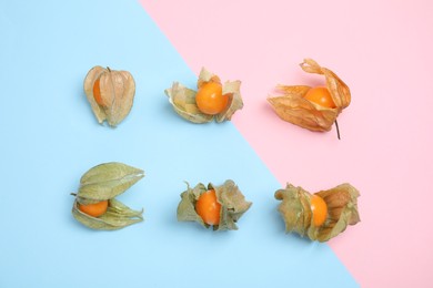 Photo of Ripe physalis fruits with dry husk on color background, flat lay